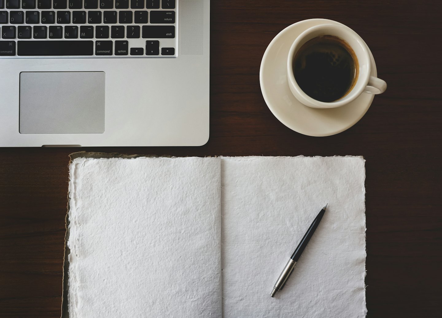 Laptop and coffee on a dark wooden desk.